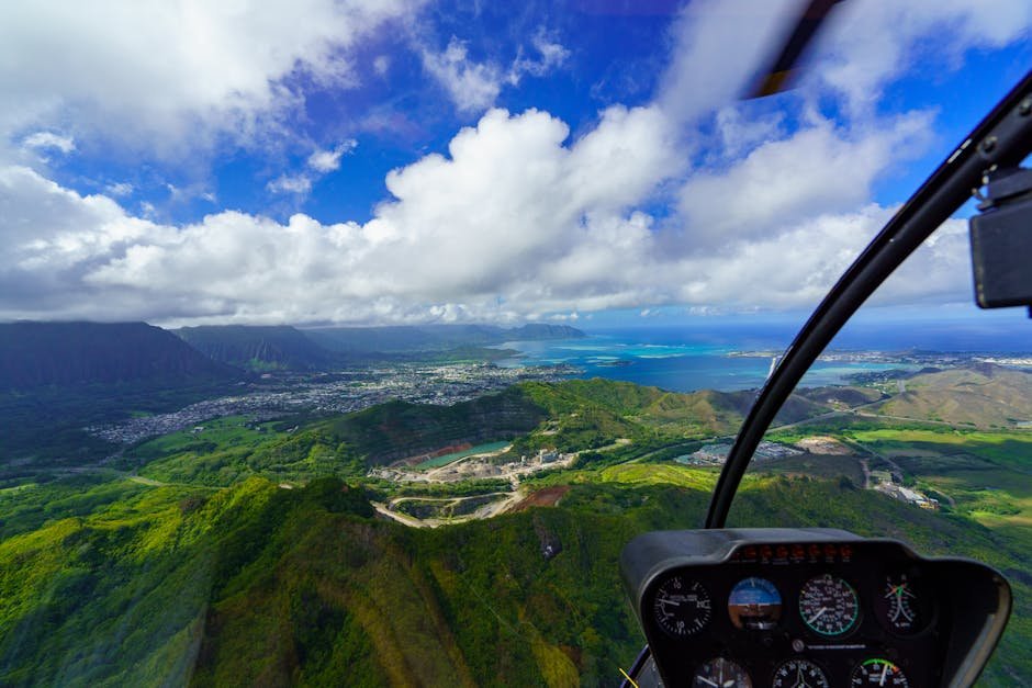 View from helicopter cockpit over green hills and ocean &mdash; the perspective of a working commercial helicopter pilot.