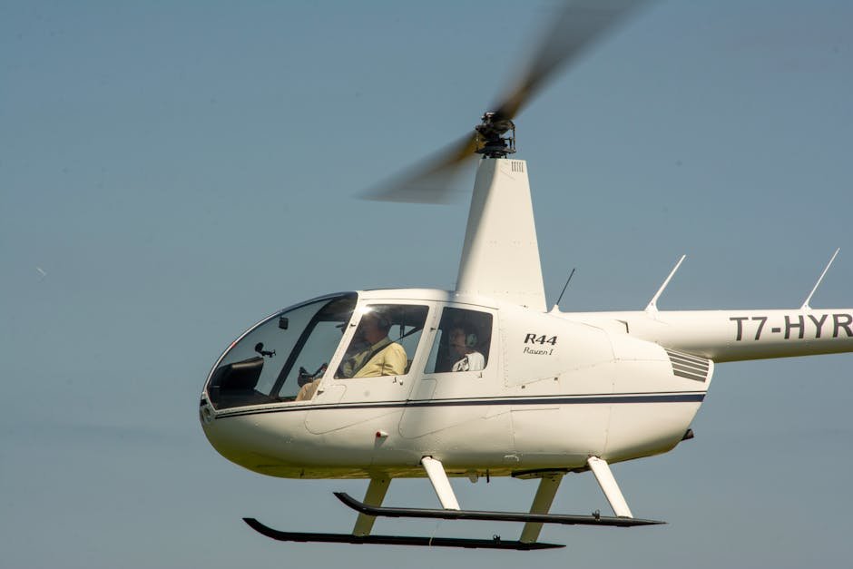 White Robinson R44 helicopter in flight with pilots inside, used by many US helicopter flight schools.