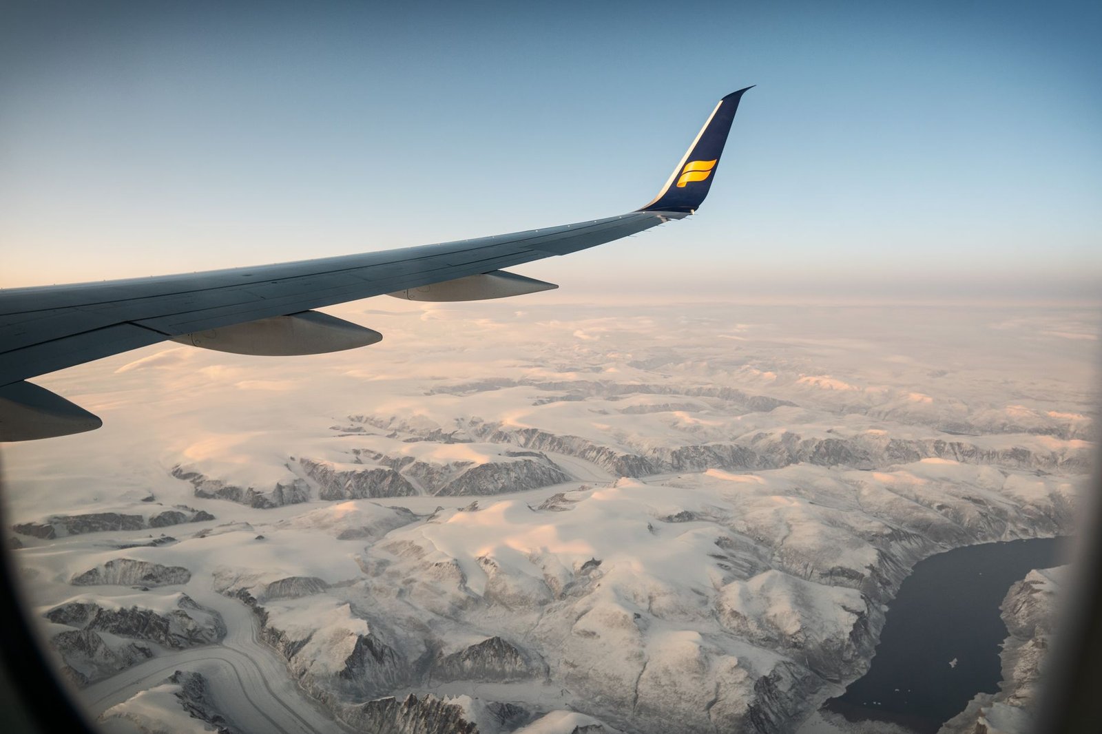 Small airplane flying over snowy mountain peaks in winter