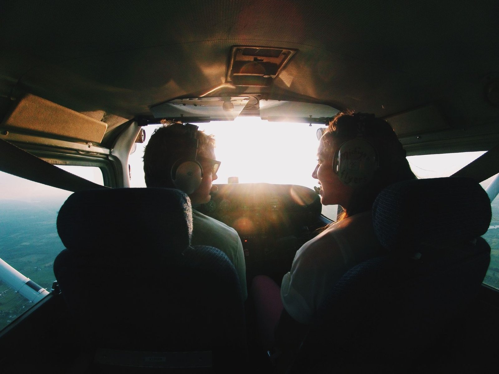 Two young student pilots flying a small aircraft at sunset