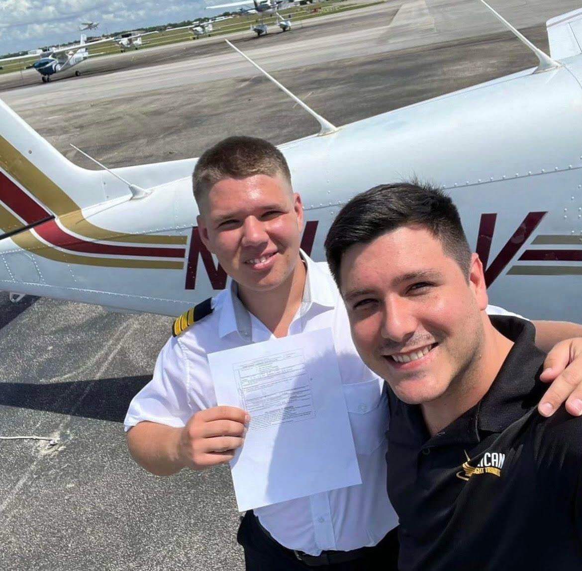 Pelican Flight School graduates celebrating near an aircraft.