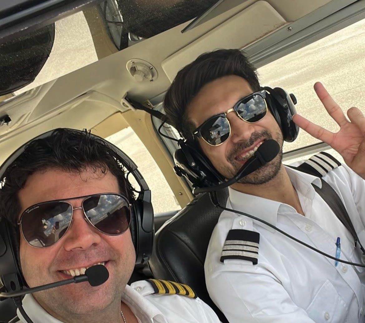 Two pilots wearing headsets inside a training aircraft.